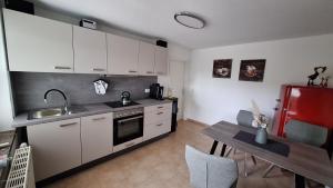 a kitchen with white cabinets and a table and a red refrigerator at Ferienwohnung Feldblick in Upahl