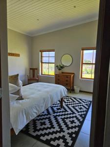 a bedroom with a bed and a mirror and windows at Lowergroen Guestfarm, Working Farm in Swellendam