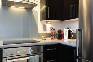 a kitchen with black cabinets and a stove top oven at Modern 1 Bed Apt with parking in Portsmouth