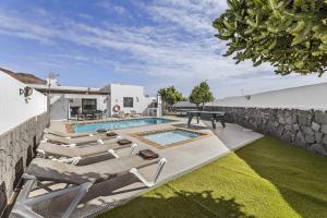 a backyard with a pool with lounge chairs and a table at Villa Bezanilla - VipVipVillas in Playa Blanca
