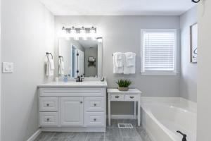 a white bathroom with a sink and a tub and a mirror at Fully Fenced & Stylish 3BR Near LakePoint Sports in Cartersville +27 photos