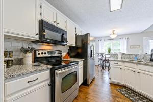 a kitchen with white cabinets and a stove top oven at Fully Fenced & Stylish 3BR Near LakePoint Sports in Cartersville