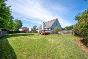 a yard with a blue house and a fence at Fully Fenced & Stylish 3BR Near LakePoint Sports in Cartersville