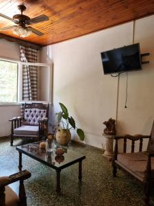 een woonkamer met een bank en een tv aan de muur bij Acutí Departamento in Puerto Iguazú