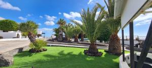 un patio con palmeras y césped verde en Renovated Villa Mahalo with swimming pool & tennis court, en Tías