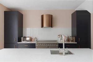- une cuisine avec des placards noirs et un évier dans l'établissement Stylish home in the perfect location, à Londres