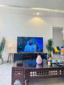 a living room with a tv and a table at شالية راقي بمسبح وجلسات خارجية in ‘Ilb