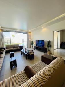 een grote woonkamer met banken en een televisie bij شالية راقي بمسبح وجلسات خارجية in ‘Ilb