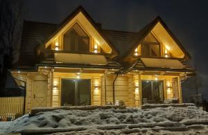 ein Blockhaus mit Lichtern auf einem Stapel Schnee in der Unterkunft Domki Hygge Tatra Luxury Chalet in Murzasichle