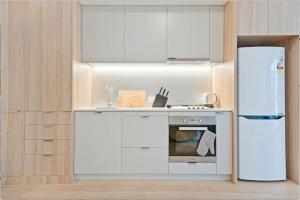  La cuisine est équipée de placards blancs et d'un réfrigérateur. dans l'établissement Stylish 1BR Entire CBD Apt 5 Minutes Train Station, à Sydney