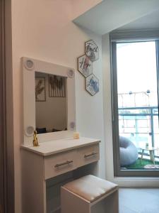 a bathroom with a vanity with a mirror and a window at Azure North Staycation by 7TwentySix CRIB in San Fernando