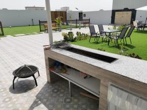 fregadero en la parte superior de un patio con mesa y sillas en alshahad chalet, en Bārsit 4 fotos más