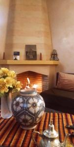 a living room with a fireplace and a table with a candle at maison d'hôtes Le petit jardin Marrakech in Marrakech