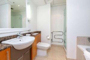 ein Badezimmer mit einem Waschbecken, einem WC und einem Spiegel in der Unterkunft Viaduct Stunner in Auckland