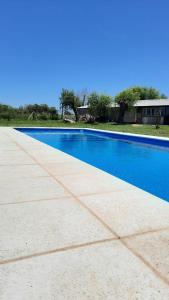 a blue swimming pool with a house in the background at La Quinta de LOS ABU in Ramallo
