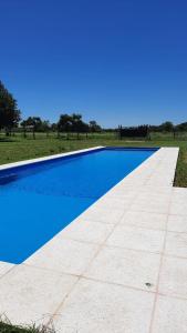 a blue swimming pool in a field with a blue sky at La Quinta de LOS ABU in Ramallo