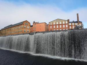 une cascade sur le côté d'une rivière avec des bâtiments dans l'établissement Mysig lägenhet i City, à Norrköping