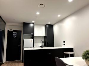 een keuken met zwarte kasten en een witte koelkast bij Top Floor Vincent in Auckland