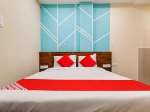OYO Hotel 56 INDORI في إندوري: غرفة نوم بسرير كبير ومخدات حمراء