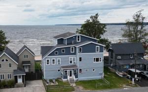 een groot blauw huis voor het water bij The Historic Oneida Lake House - Condo 4 in Blossvale