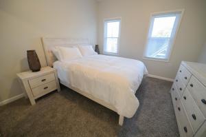 ein Schlafzimmer mit einem Bett, einer Kommode und zwei Fenstern in der Unterkunft The Historic Oneida Lake House Condo 5 (Penthouse) in Blossvale
