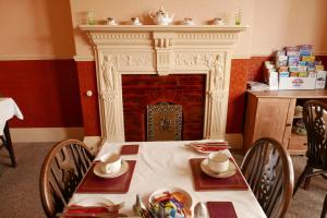 a dining room with a table and a fireplace at Abbey Guest House in Norwich
