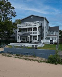 une grande maison blanche avec une grande véranda à l'avant dans l'établissement The Historic Oneida Lake House - Condo 1, à Blossvale