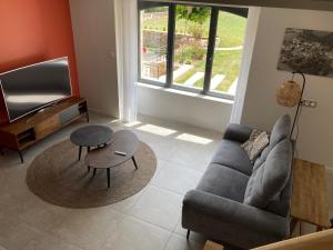 sala de estar con sofá, mesa y TV en Maison village de charme, en Montrozier