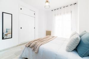 Dormitorio blanco con cama con almohadas azules en Piso completo junto a parada de Metro, en Maracena