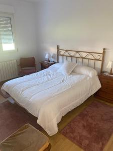 a bedroom with a large white bed and a chair at BAHIÑA MAR in Baiona