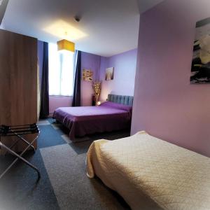 a purple bedroom with two beds and a window at Logis Hôtel & Restaurant Le Saint Savinien in Saint-Savinien