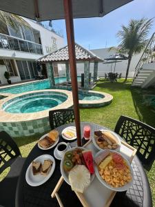 a table with plates of food on a table with a pool at WL IMPERIO HOTEL POUSADA in Canoa Quebrada