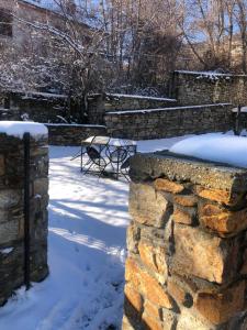 eine Steinmauer mit einer Bank im Schnee in der Unterkunft Guesthouse Kontogianni - Materka in Nymfaio
