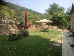 a garden with a table and an umbrella and chairs at Guesthouse Kontogianni - Materka in Nimfaíon