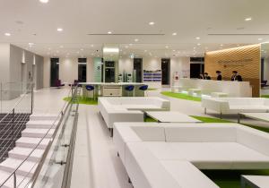 a lobby with white furniture and people in the background at Daiwa Roynet Hotel Numazu in Numazu