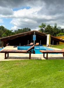 a pool with two benches and a building at Chácara em Guararema in Guararema