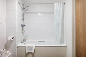 a bathroom with a tub and a shower curtain at Bright & Immense 2 BDR Flat near Excel Center in London