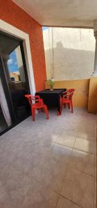 un patio con una mesa negra y 2 sillas rojas en Piso completo. Hasta 9 personas. Norte MID, en Mérida