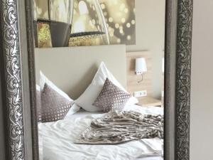 ein Spiegel, der ein Bett mit weißer Bettwäsche und Kissen reflektiert in der Unterkunft Weingut Bastian in Brauneberg