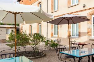 patio ze stołami, krzesłami i parasolami w obiekcie ibis Styles Toulouse Lavaur w mieście Lavaur