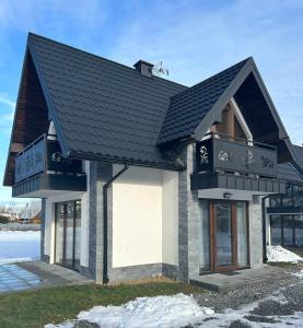 une maison avec un toit noir et un balcon dans l'établissement FAMILY HAUSE, à Witów