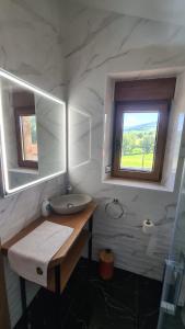 uma casa de banho com um lavatório, um espelho e uma janela em CASA RURAL LALLANTA em Pedroso