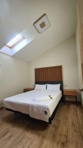 1 dormitorio con 1 cama blanca grande y tragaluz en CASA RURAL LALLANTA, en Pedroso