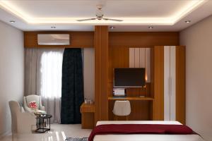 - une chambre avec un lit, une télévision et une chaise dans l'établissement Hotel Priyadarsini, à Bānkura