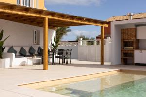 un patio con pergolato in legno e una piscina di Casa Nahia a Corralejo