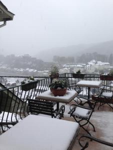 un balcón con mesas y sillas en la nieve en Le Cosy Hotel Restaurant, en Bouillon
