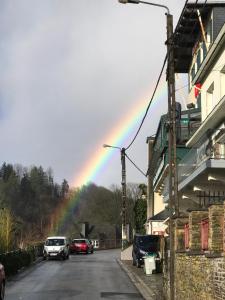 un arco iris en el cielo sobre una calle con coches en Le Cosy Hotel Restaurant en Bouillon