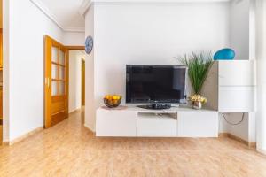 una sala de estar con TV de pantalla plana en un armario blanco en Sunny apartment in Torrevieja ,100 meters from Los Locos beach, en Torrevieja