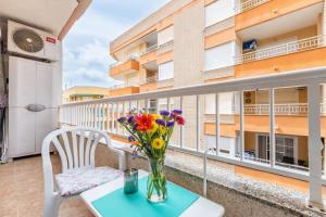un jarrón de flores sentado en una mesa en un balcón en Sunny apartment in Torrevieja ,100 meters from Los Locos beach, en Torrevieja
