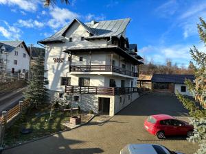 a house with a car parked in a parking lot at Pensiunea Solca in Solca +4 photos